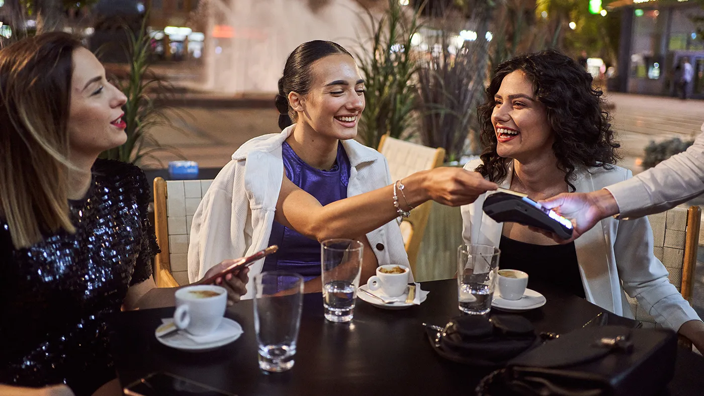 Ladies paying for coffee on patio using mastercard