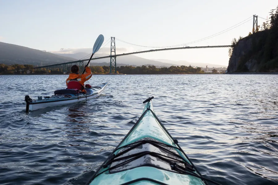 A couple kayaking in Vancouver underneath the Lions Gate bridge.
