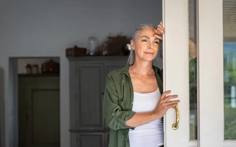 Retired woman looking out her sliding door