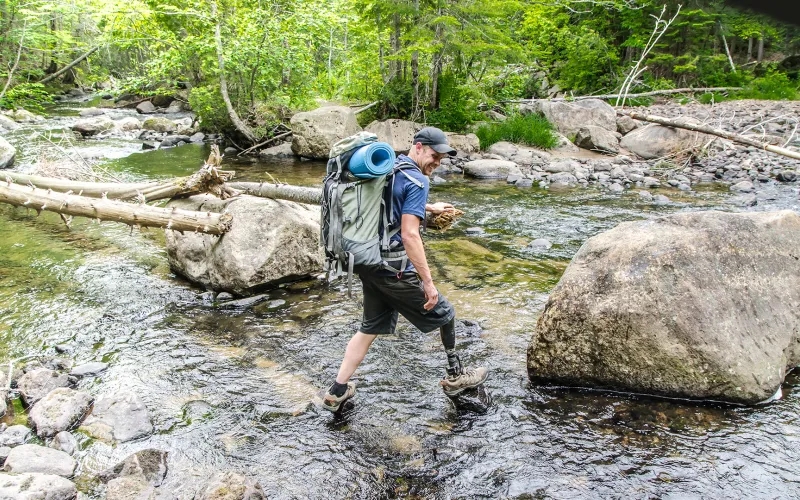 Man hiking across creek