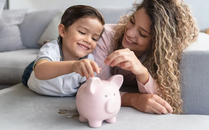 Mom and child on bed with piggybank