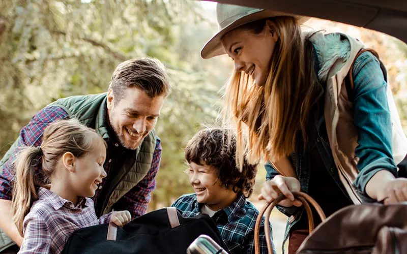 Family unpacking their car in a forest