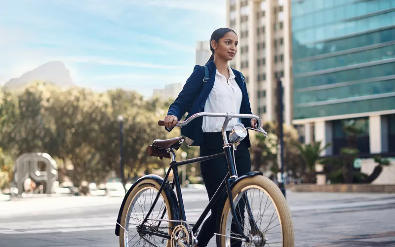 Woman walking with a bike through a city.