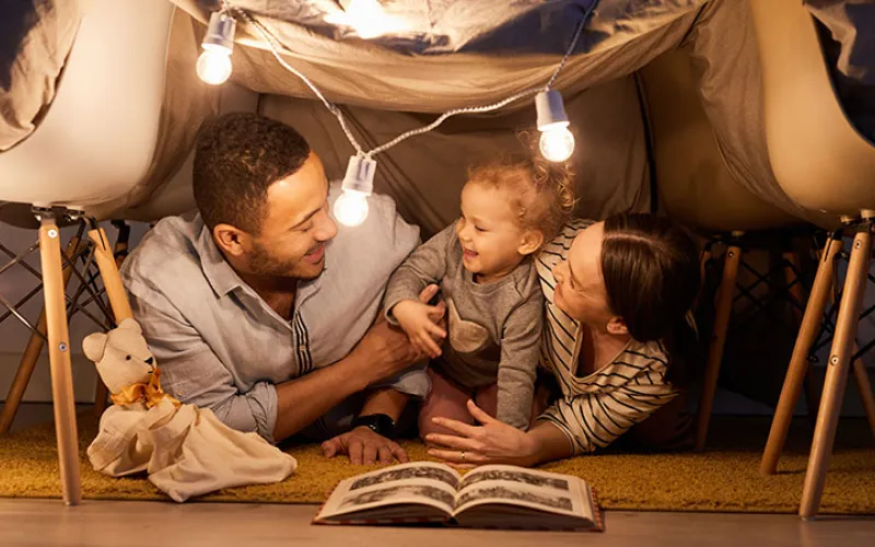 Mother, father and child reading a book at home