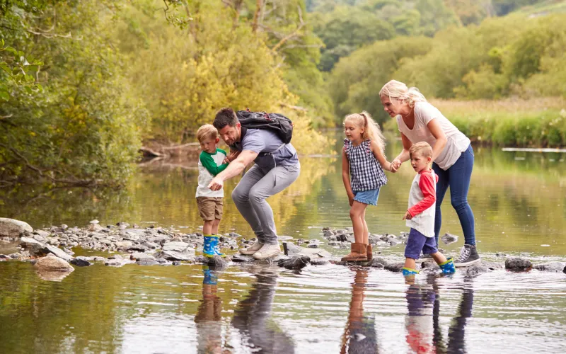 A family at the rivers edge, looking for fish in the water.