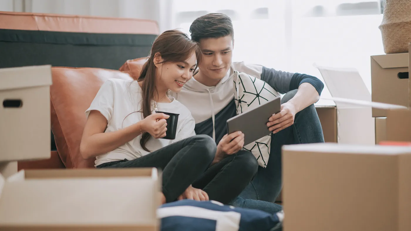 Couple sitting in new home reading tablet