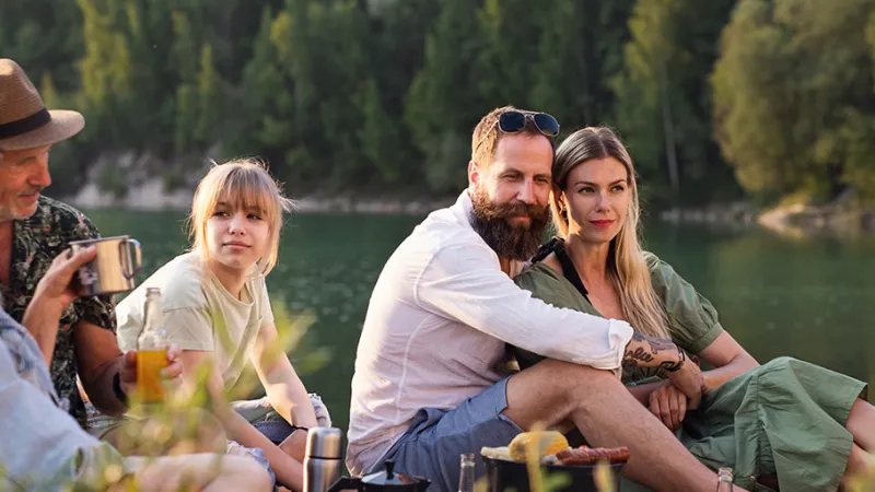 A family sitting with each other beside a lake.